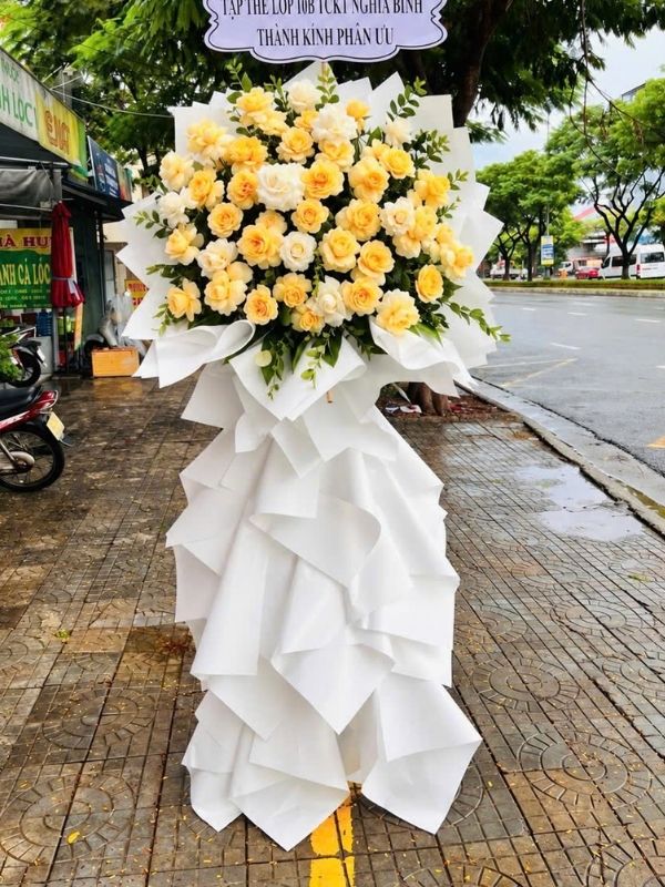 Màu sắc: đỏ. Dịp tặng: lễ viếng, lễ tang, lễ nhập quan, tiễn biệt, chia buồn. Loại sản phẩm: Hoa chia buồn / hoa tang lễ.

Vòng Hoa Đám Tang Cao Cấp - HCB.74 là mẫu kệ hoa cao cấp phúng viếng, được Hoa Mãi Mãi hoàn thiện tỉ mỉ từng chi tiết để thể hiện sự trân trọng, tiếc thương dành cho người đã khuất trong từng nghi lễ tang ma.

Tông màu trắng bạc điểm hồng phấn xuyên suốt thiết kế giúp sản phẩm toát lên khí chất trầm lắng, trang trọng, đúng tinh thần của một sản phẩm hoa chia buồn, phúng viếng.

Sản phẩm nổi bật với lan mokara trắng và hồng phấn nhạt làm trung tâm, xen kẽ lá bạc (dương xỉ bạc), nơ sọc đen trắng tạo nên bố cục hài hòa, không quá cầu kỳ nhưng vẫn toát lên sự chỉn chu trong từng chi tiết nhỏ.

Sản phẩm cao khoảng 1,8 – 2,0m, đường kính phần hoa chính 70 – 90cm khi hoàn thiện, đủ để tạo điểm nhấn trang trọng trong không gian lễ viếng; kích thước có thể thay đổi theo yêu cầu cụ thể của quý khách.

Thông điệp gửi viếng: đi kèm bảng chữ chia buồn trang nghiêm, có thể ghi "Thành kính phân ưu", "Vô cùng thương tiếc" hay lời tiễn biệt riêng theo mong muốn của người gửi.

Tùy biến mẫu theo yêu cầu: Đội ngũ Hoa Mãi Mãi sẵn sàng hỗ trợ tùy chỉnh mẫu hoa theo yêu cầu về màu sắc, kiểu dáng và kích thước, đồng thời đảm bảo chất lượng hoa tươi cùng dịch vụ giao hàng nhanh chóng, đúng giờ tổ chức lễ tang.
