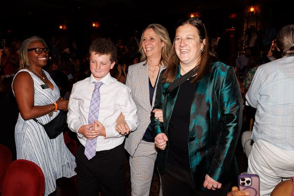 A woman in a gray suit walks arm-in-arm with her wife and their son.