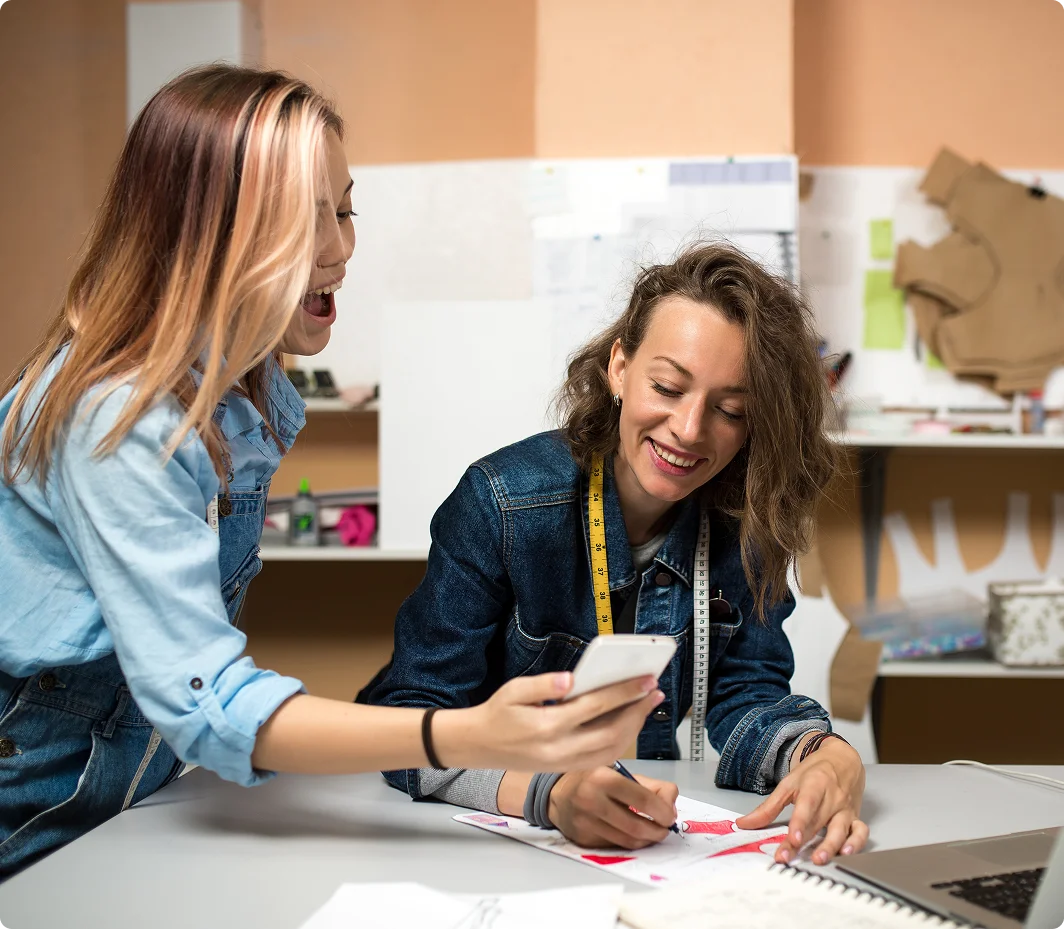 Two educators looking at smart phone while preparing a sewing project
