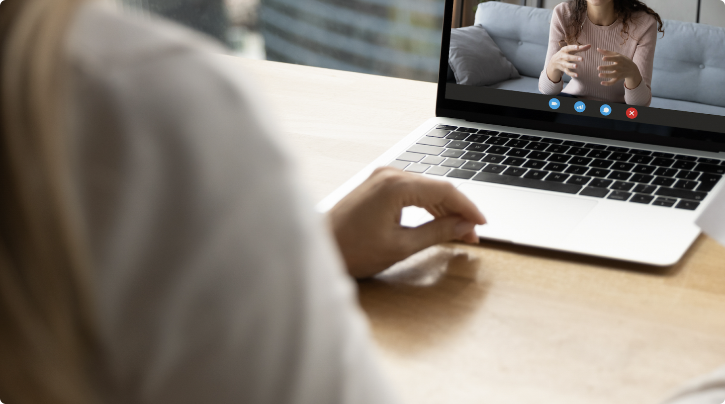 A laptop on a desk with a person speaking on the video screen