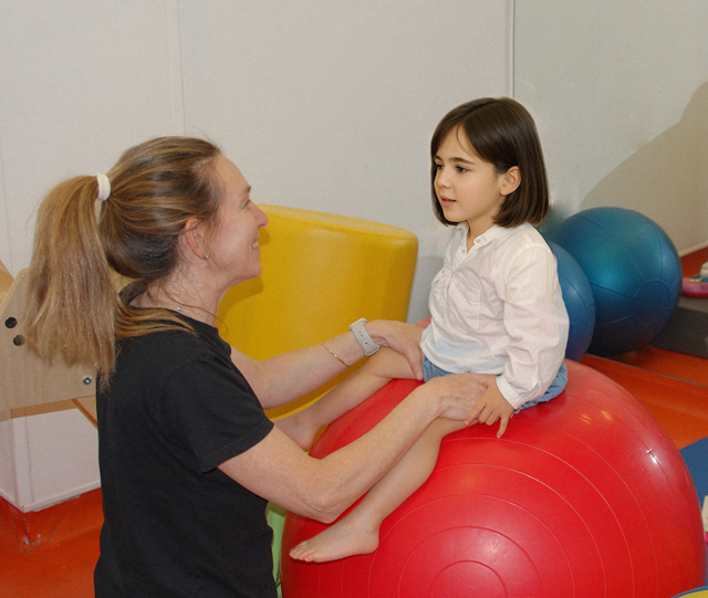 niña sentada en una pelota roja