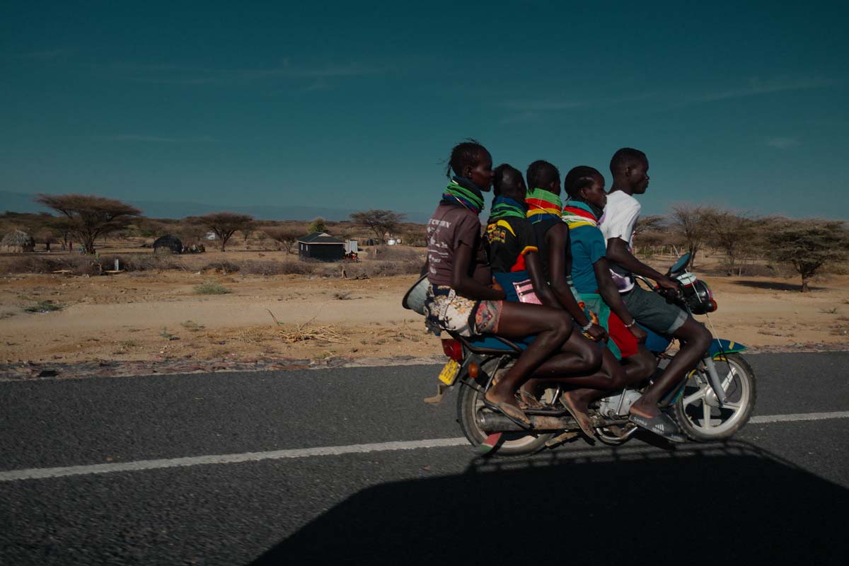 A motorbike carrying several passengers along the road in Kakuma
