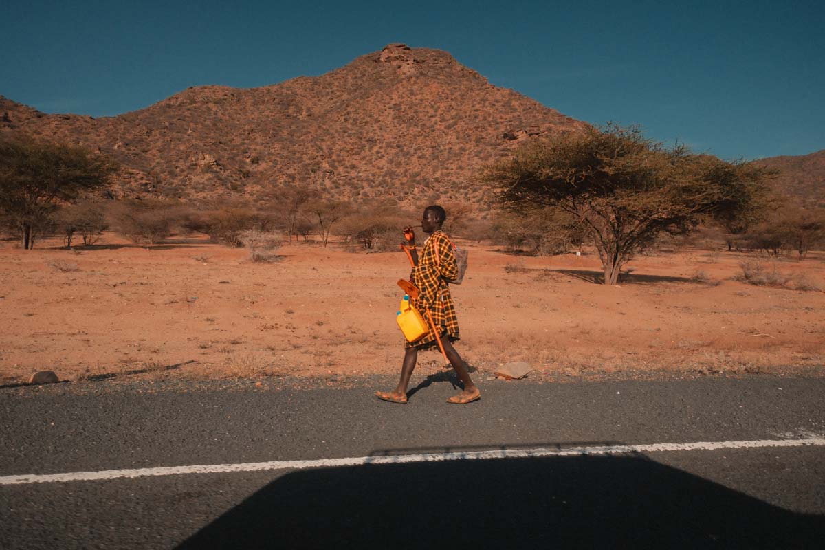 A person in yellow walking beside the road in Kakuma