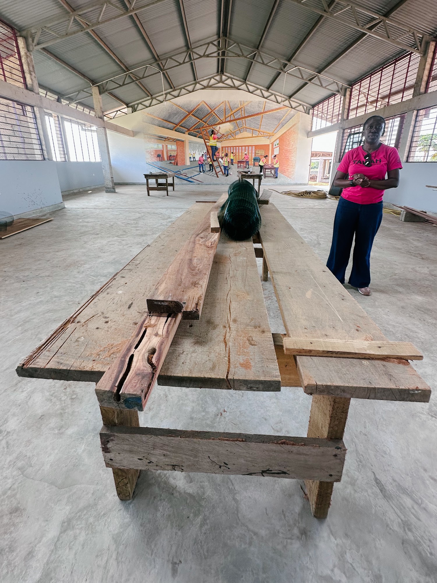 Victoria standing beside a long timber workbench in an open hall on the campus