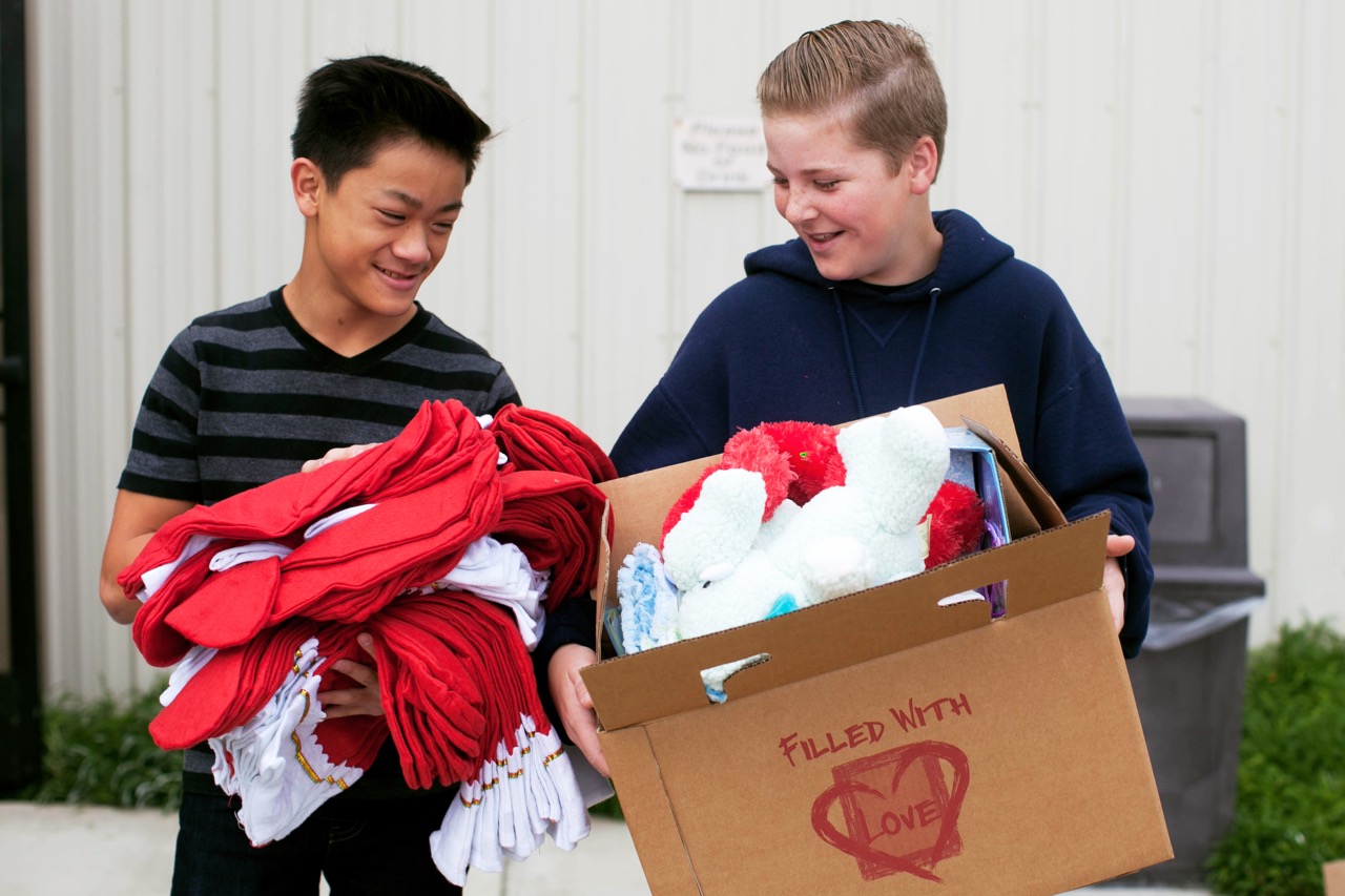 Two volunteers carrying gifts and red shirts for Boxes of Love