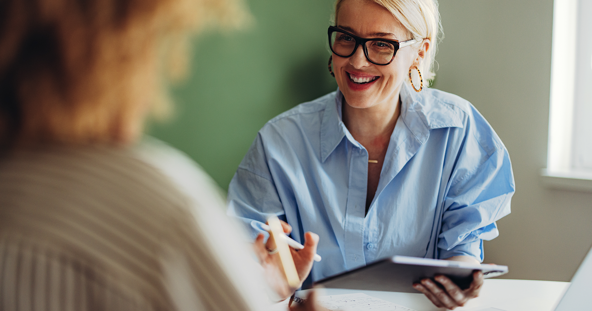 Frau erklärt der Kollegin den unterschied zwischen eines digitalen Dokumentenmanagers und Word