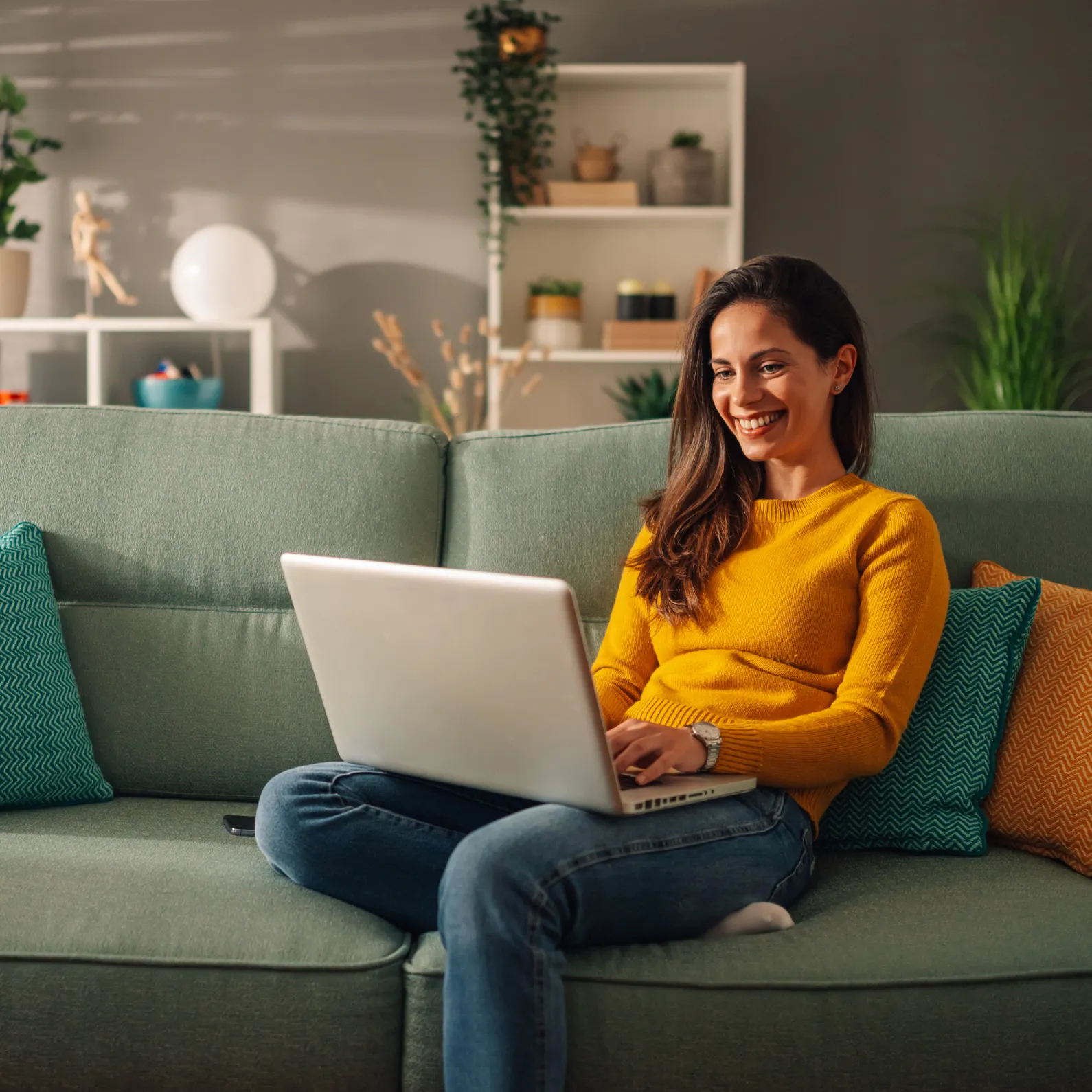 Eine Frau sitzt entspannt auf dem Sofa und nutzt ihren Laptop, um über Employee Self Service eigenständig HR-Anliegen digital zu erledigen.