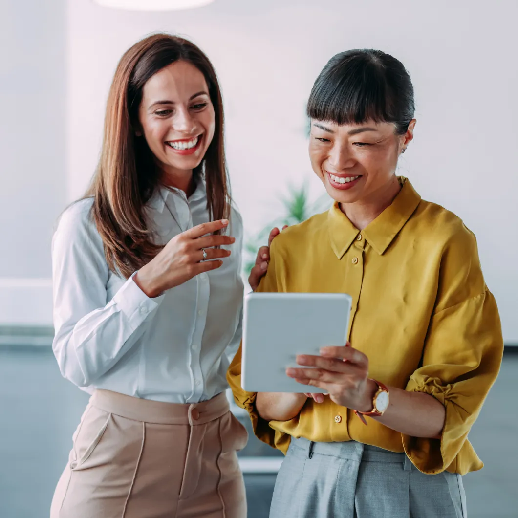 Zwei Mitarbeiterinnen nutzen ein Tablet, um eine digitale Unterschrift zu leisten.
