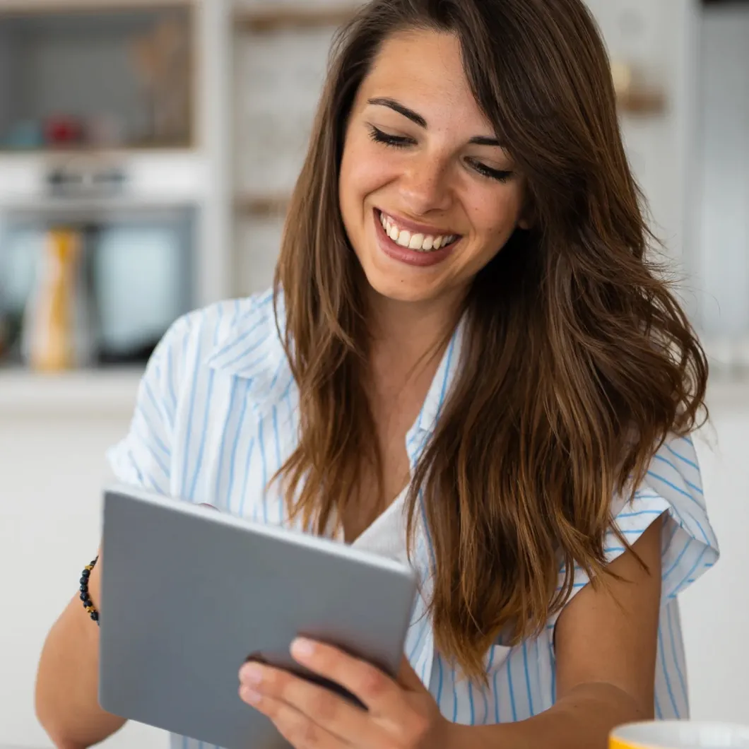 Frau nutzt Tablet am Schreibtisch mit Notizen und Kaffeetasse – Symbolbild für digitales Arbeiten mit Haufe DocPlus.