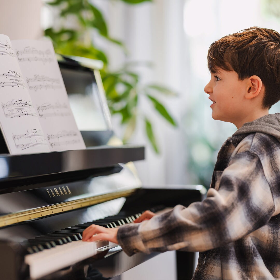 Ein Kind spielt mit Freude auf einem Klavier der B-Serie