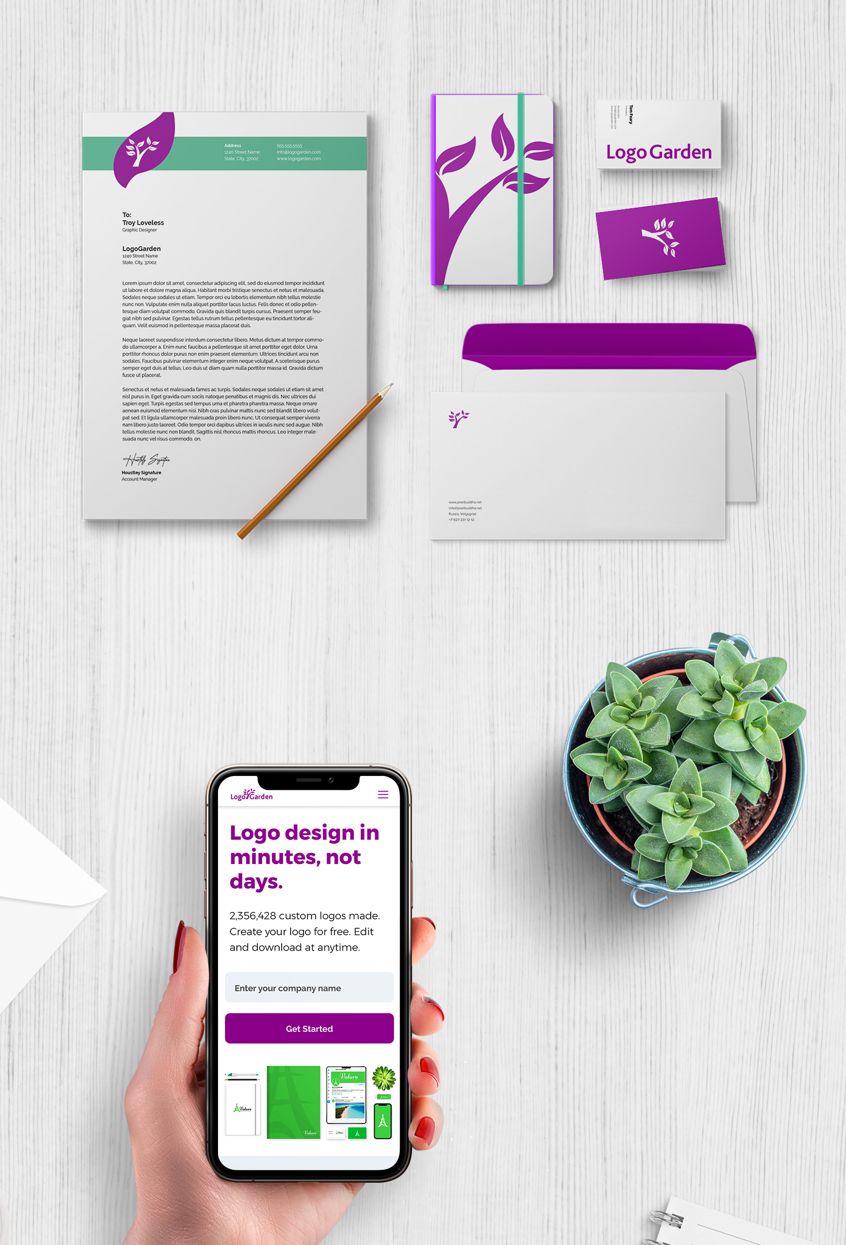 Stationery displayed on a wooden background with a lady holding a phone showcasing LogoGarden's homepage. 