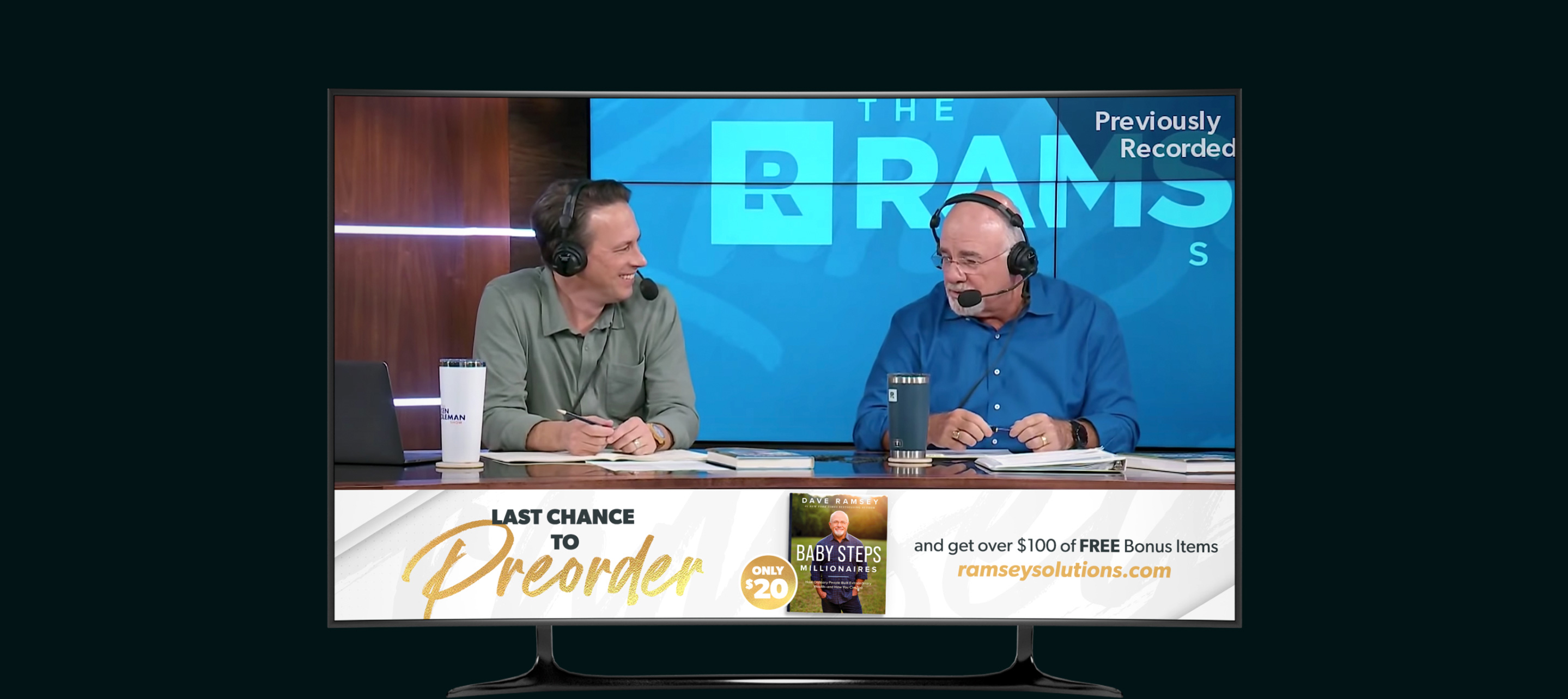 Two men wearing headsets talking on a talk show set with a blue RAMS backdrop and a preorder ad for the book 'Baby Steps Millionaires' at the bottom.