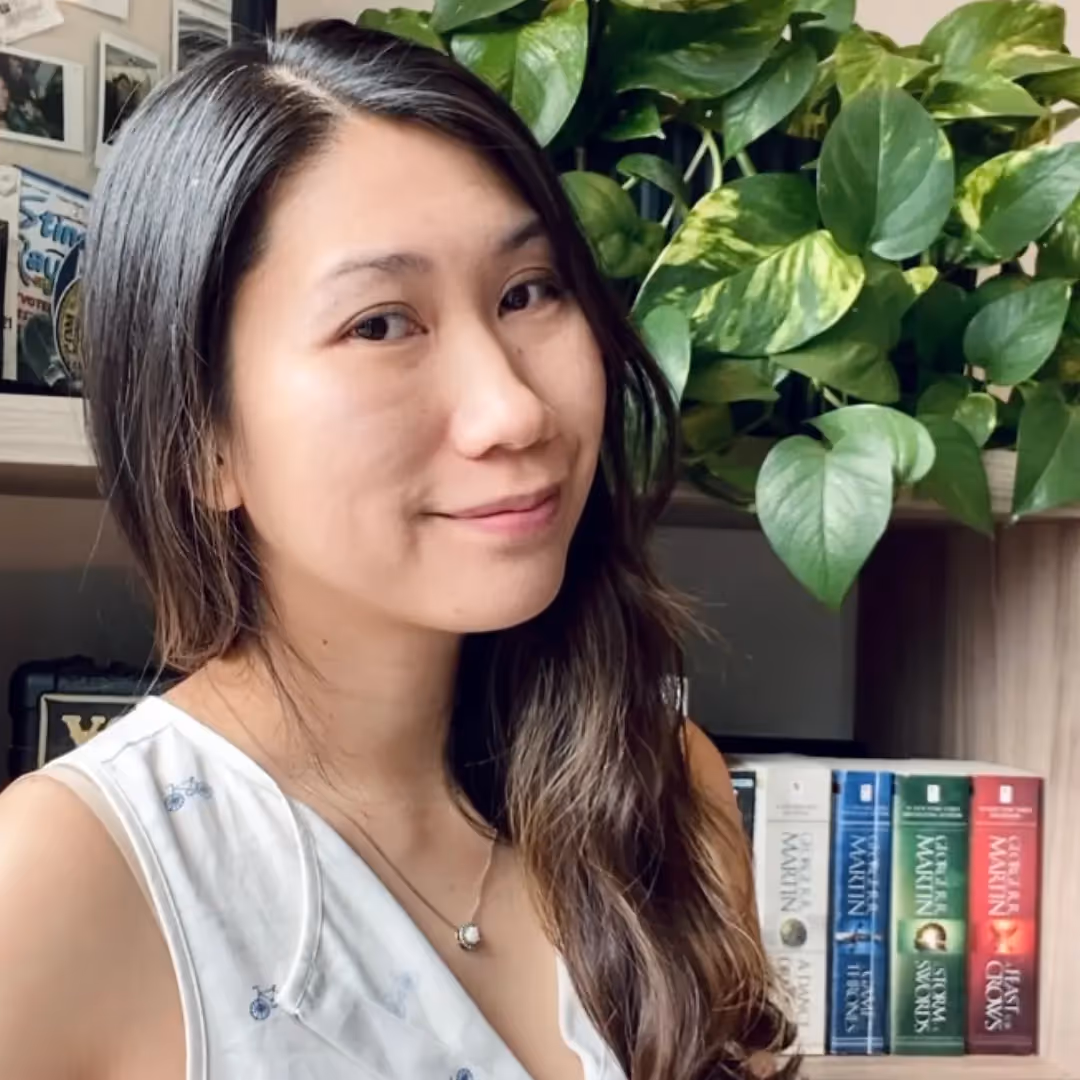 A woman smiling in front of a bookshelf. - Assistments - Formative Assessment Solutions