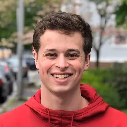 A man wearing a red hoodie smiling at the camera. - Assistments - Formative Assessment Solutions