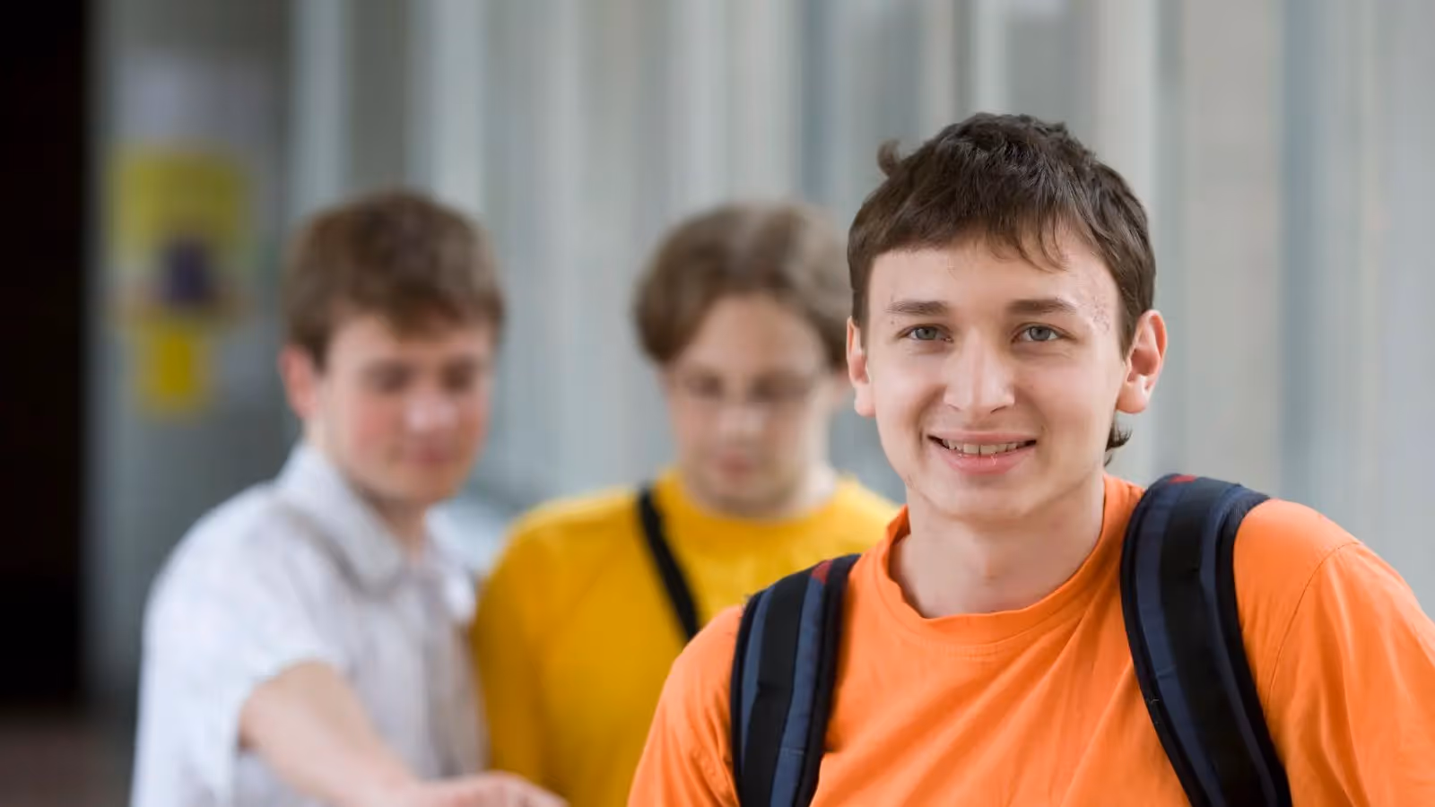 A man wearing an orange shirt and a backpack.