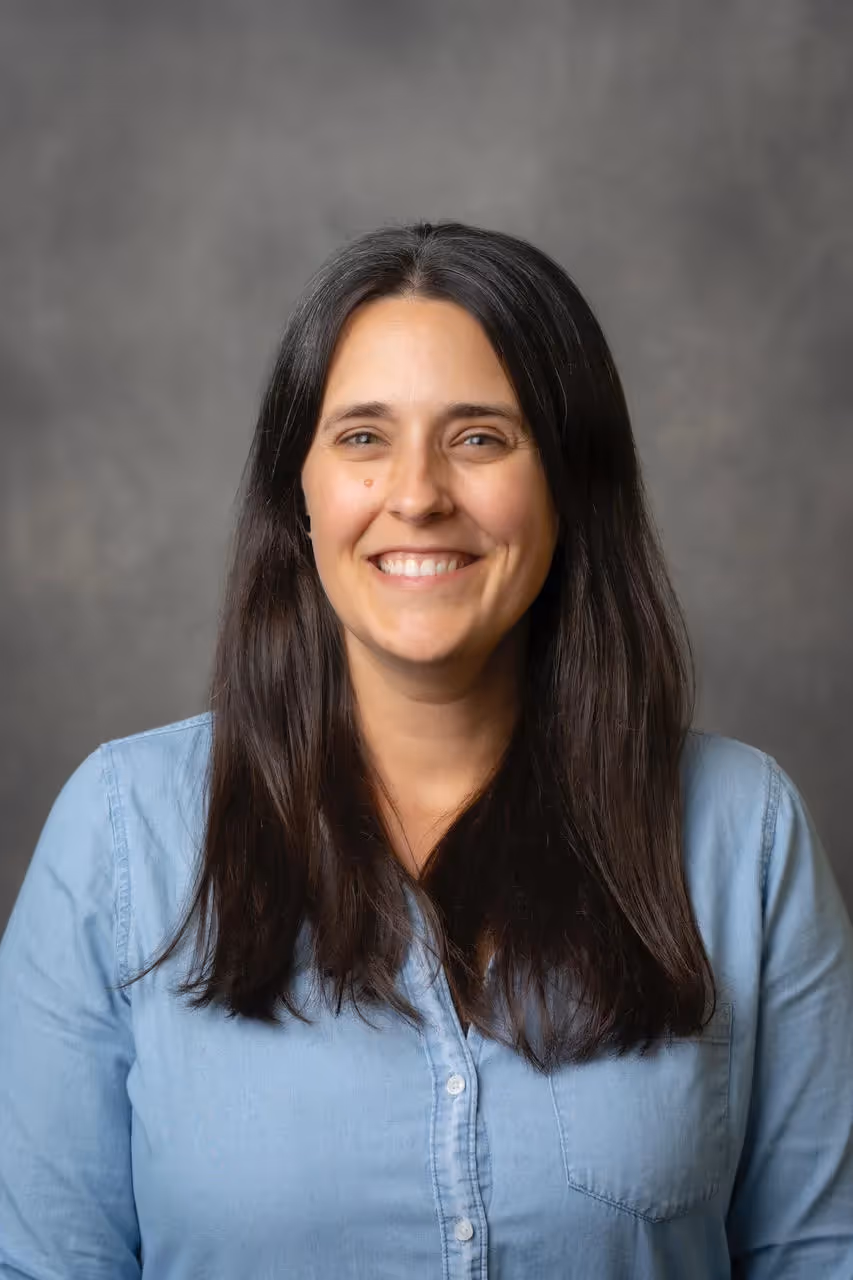 A woman with long brown hair and a blue shirt smiling. - Assistments - Formative Assessment Solutions