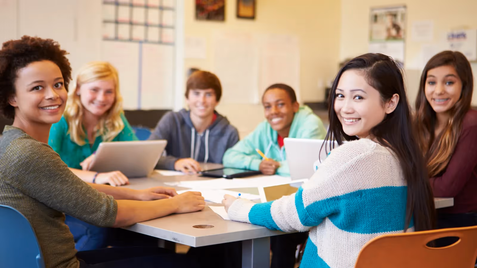 A group of students sitting around a table with laptops and papers. - ASSISTments Images