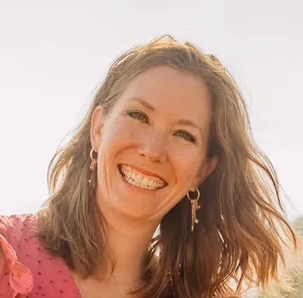 A woman with long hair and a pink shirt smiling. - ASSISTments Images