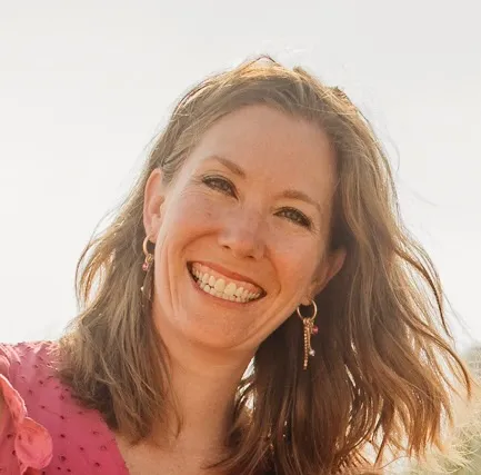 A woman with long hair and a pink shirt smiling. - ASSISTments Images
