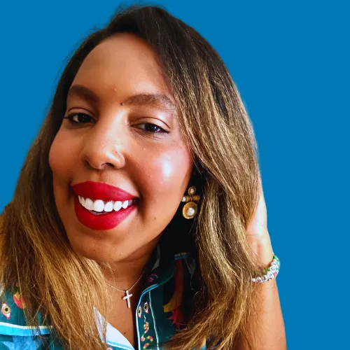 A woman with a nose piercing and red lipstick smiles for the camera. - ASSISTments Images