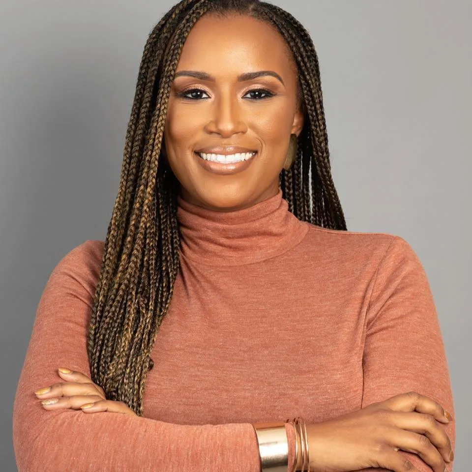 A woman with dreadlocks and a brown shirt smiling. - ASSISTments Images