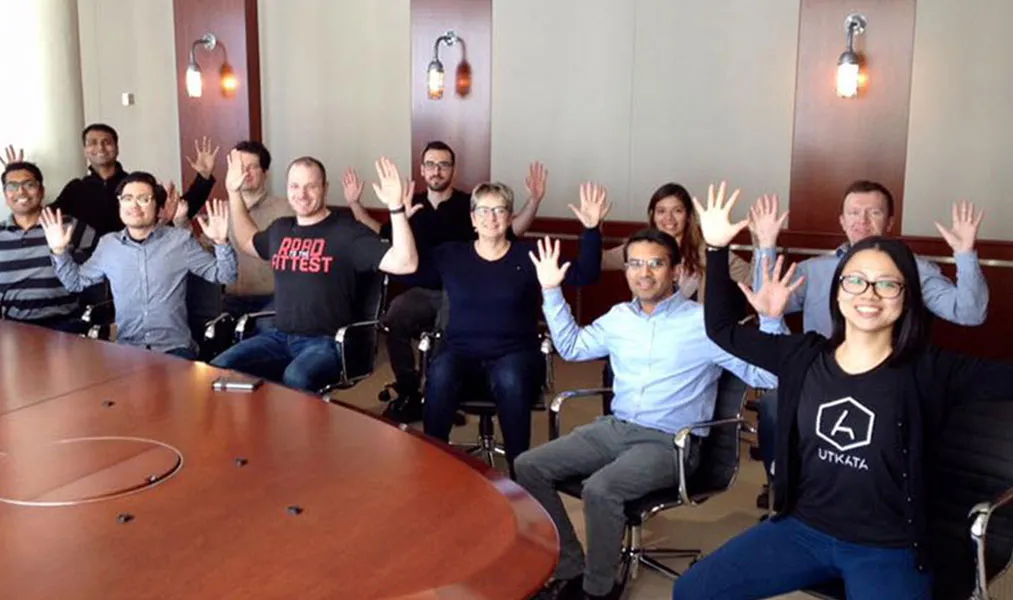 Inna leading a seated yoga session with colleagues around a boardroom table