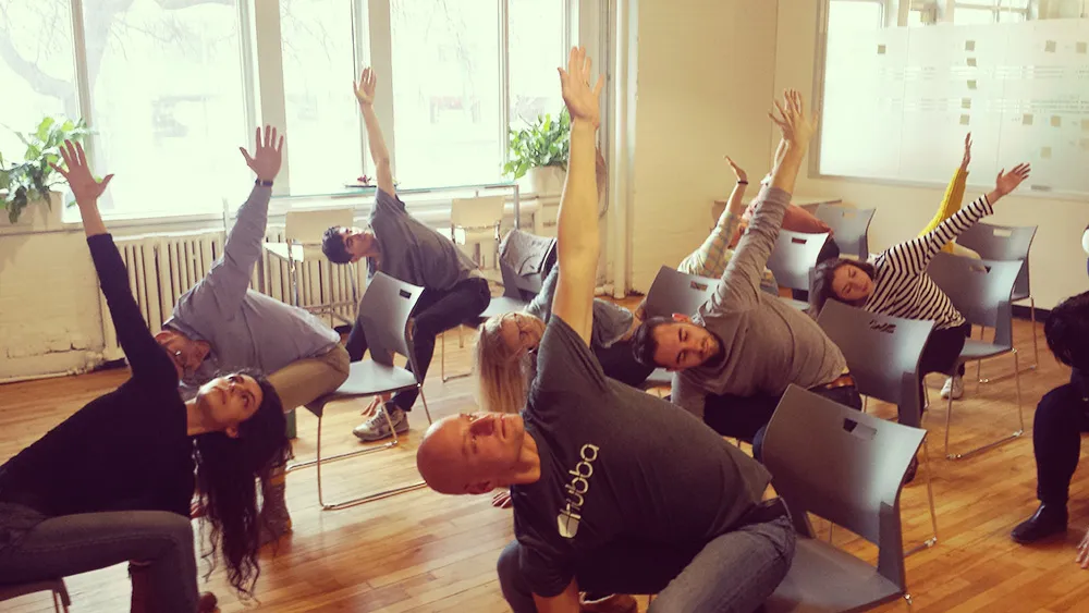 A team taking part in seated side stretches during a workplace chair yoga session