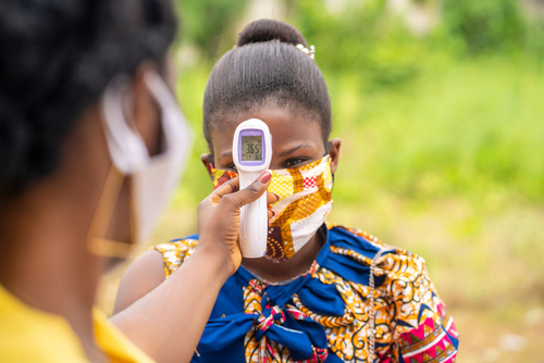 A lady having her forehead temperature taken in Ghana during covid