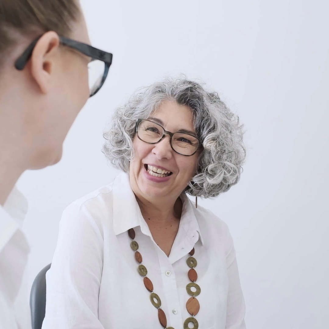 Elderly female patient smiling while speaking to dentist at le tooth