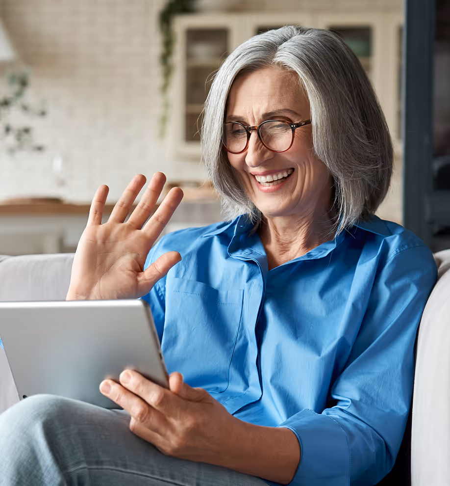 A woman sitting on a couch holding a tablet.