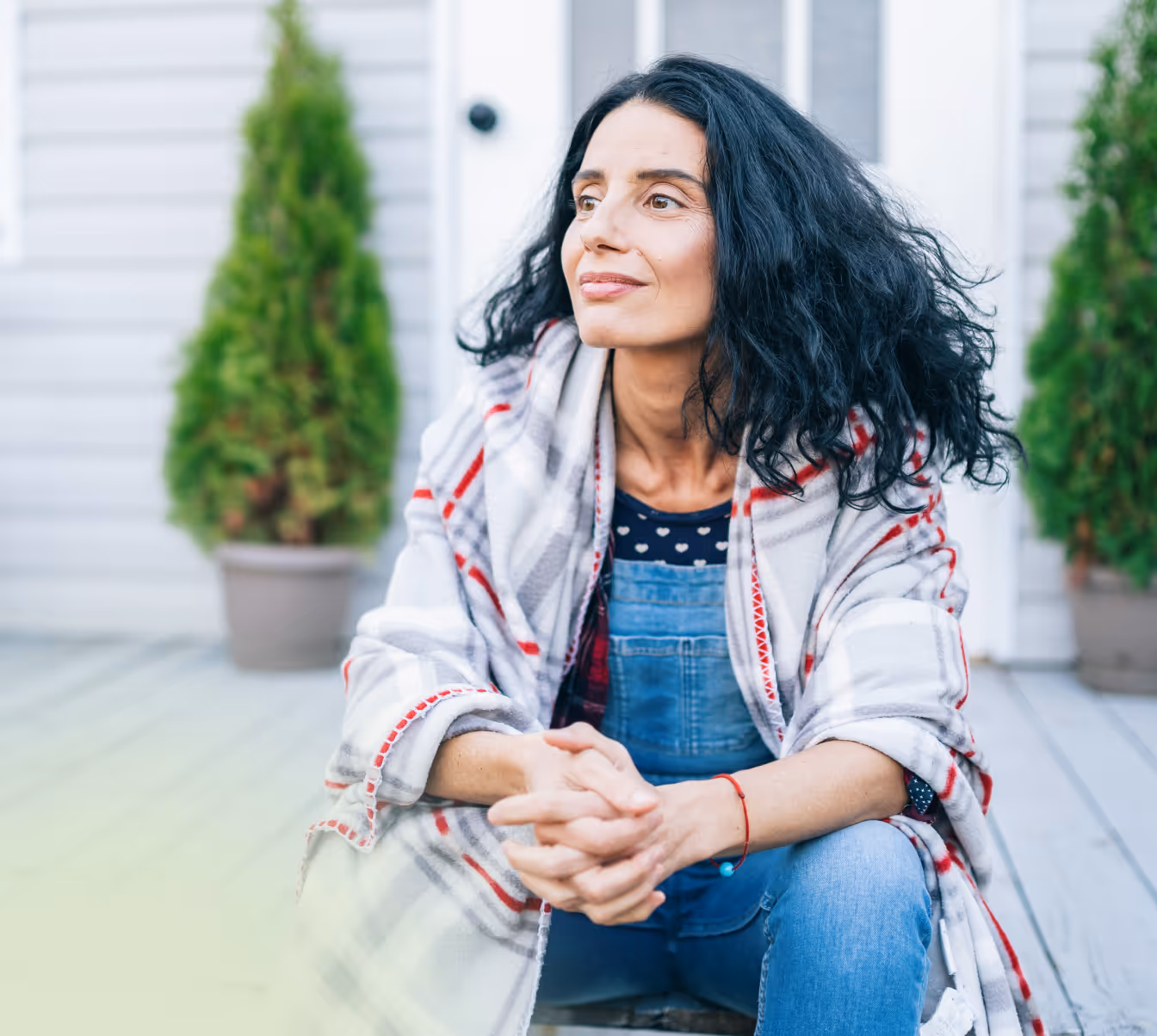 A woman sitting on a porch in front of a house.