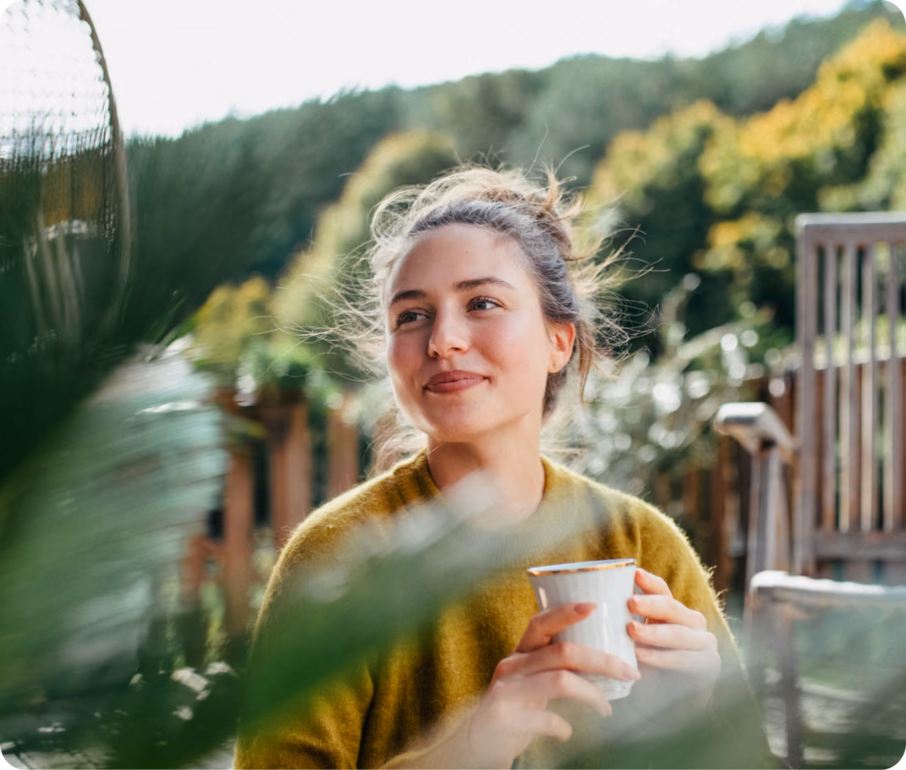 Woman smiling outdoors while holding a cup of coffee