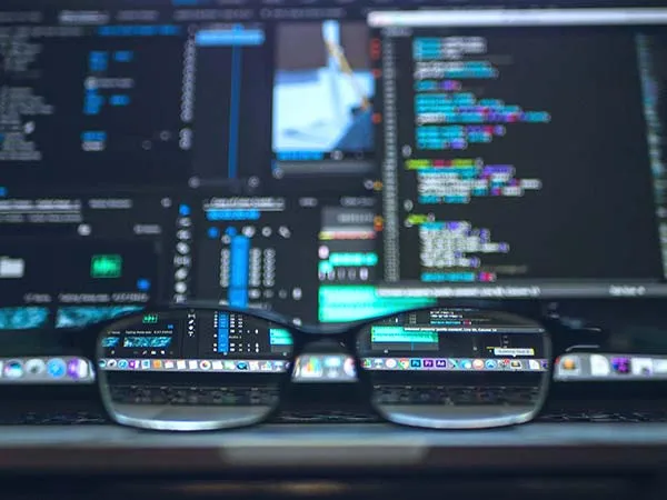 Glasses resting on laptop with coding programs on screen