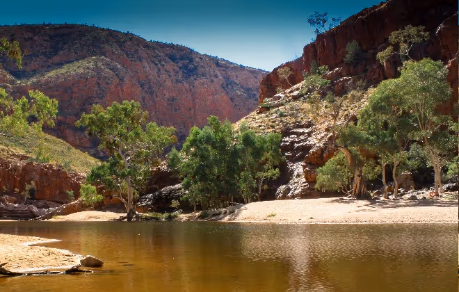 Swim in the cool waterhole beneath towering red rock walls