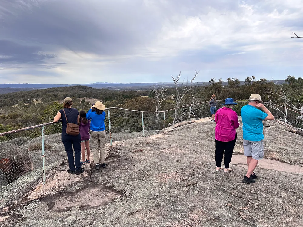A group of seniors hiking through the scenic Granite Belt, surrounded by stunning landscapes and enjoying the fresh air.