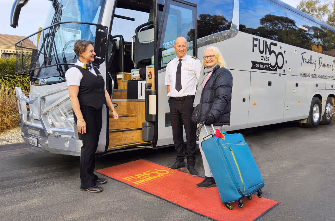 Fun Over 50 Holidays staff welcome a guest boarding a Diamond Class coach via a red carpet at the entrance