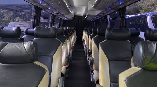 Interior of a Gold Class coach showing rows of black and beige reclining seats with blue LED lighting