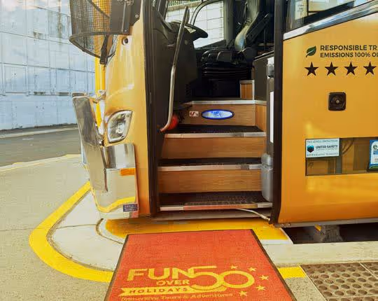 Close-up of a Gold Class coach entrance showing non-slip steps, handrail, and welcome mat