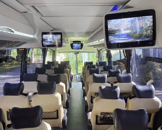 Interior of a Gold Class coach showing overhead monitors displaying onboard content