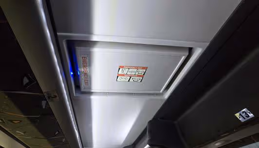 Coach ceiling showing an emergency exit roof hatch with exit and ventilation instructions
