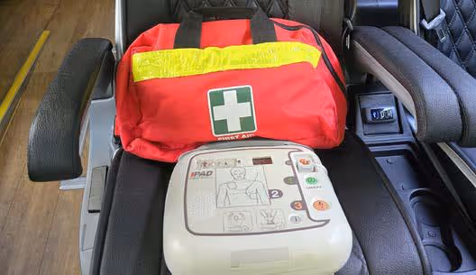 First aid kit bag and automated external defibrillator stored on a coach seat