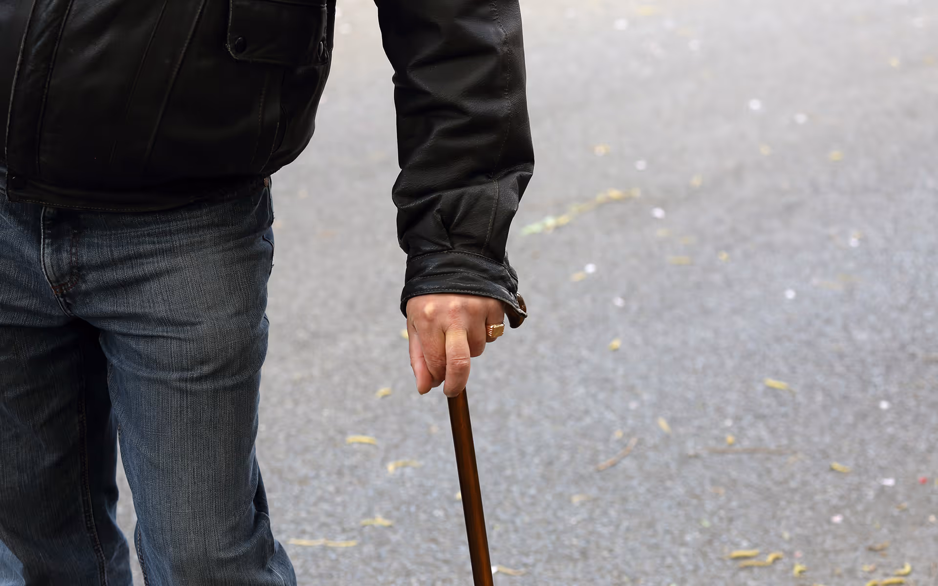Guest using a walking stick while standing on a paved path