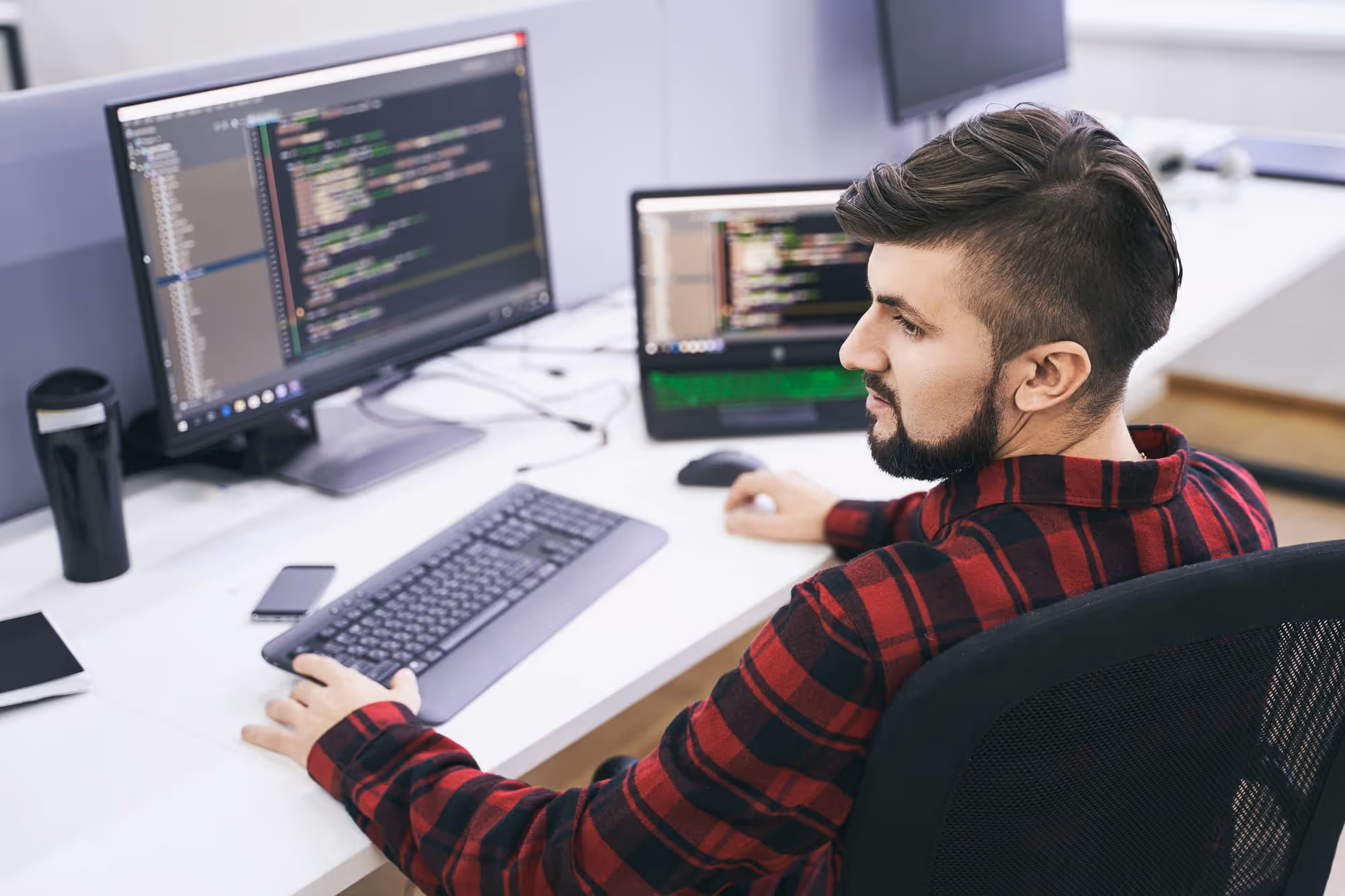 A man sitting at a desk and working on computer code