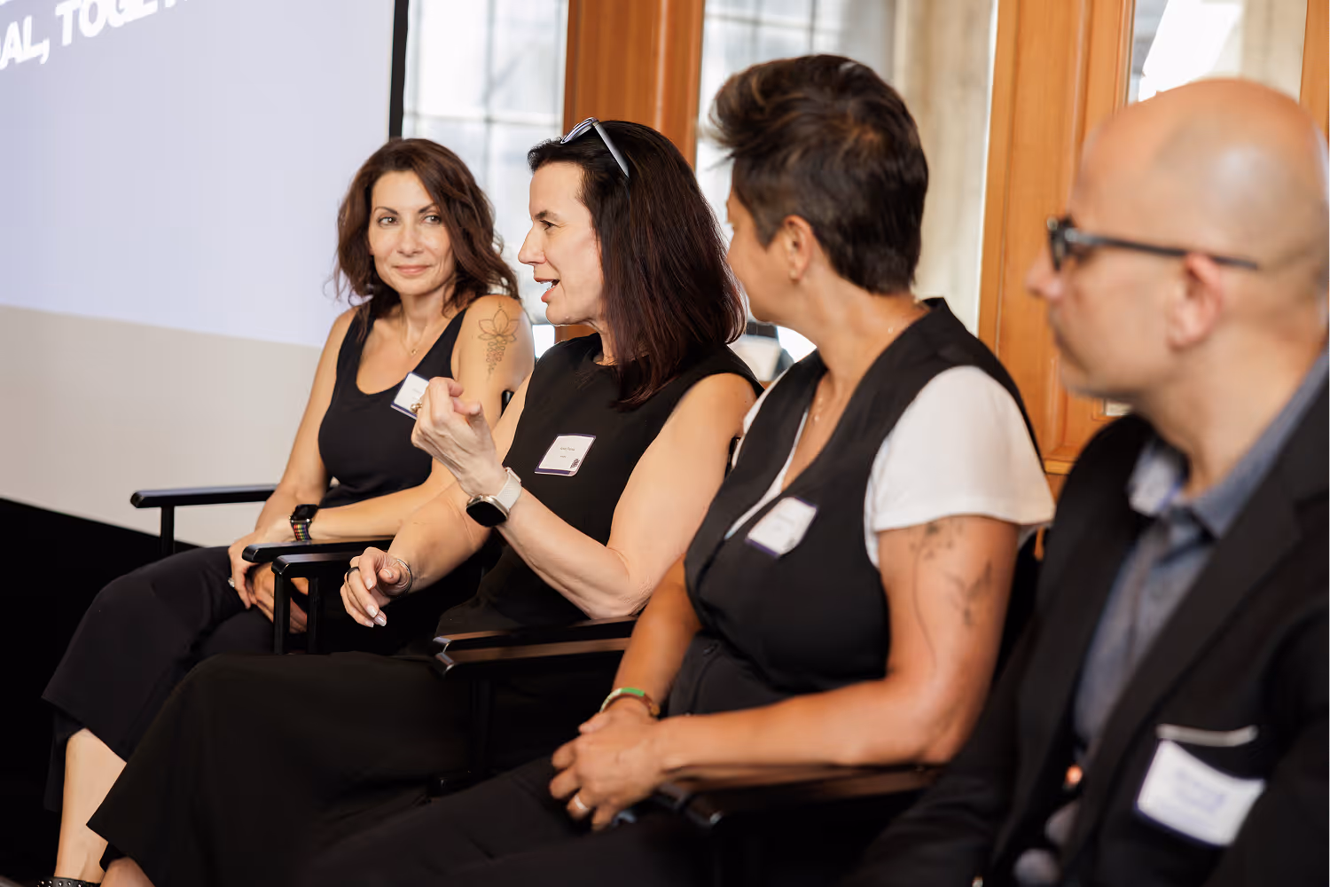 Four people seated in a panel discussion, two women speaking and others listening attentively.