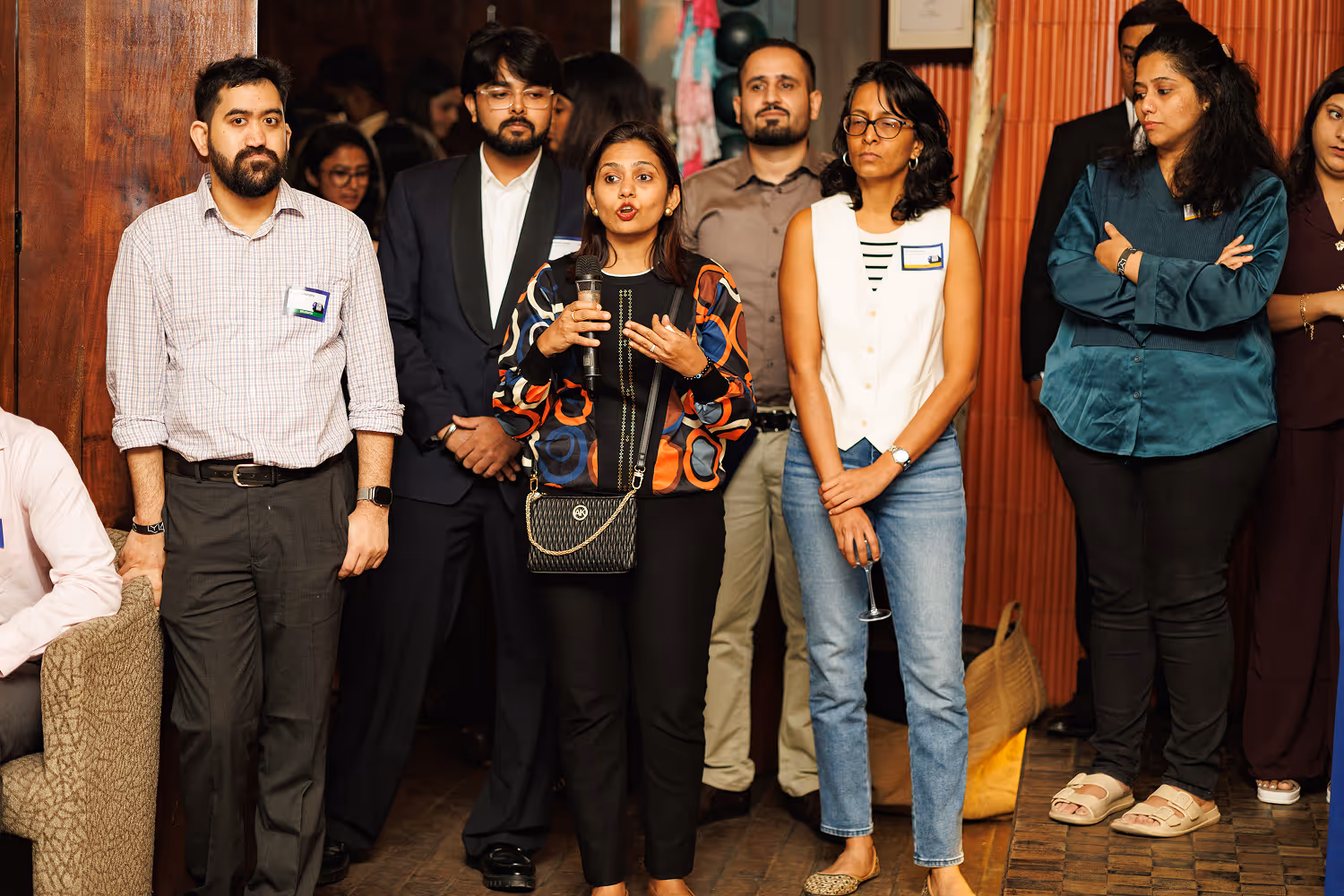 Group of people at an event, one woman speaking with a microphone while others listen attentively.