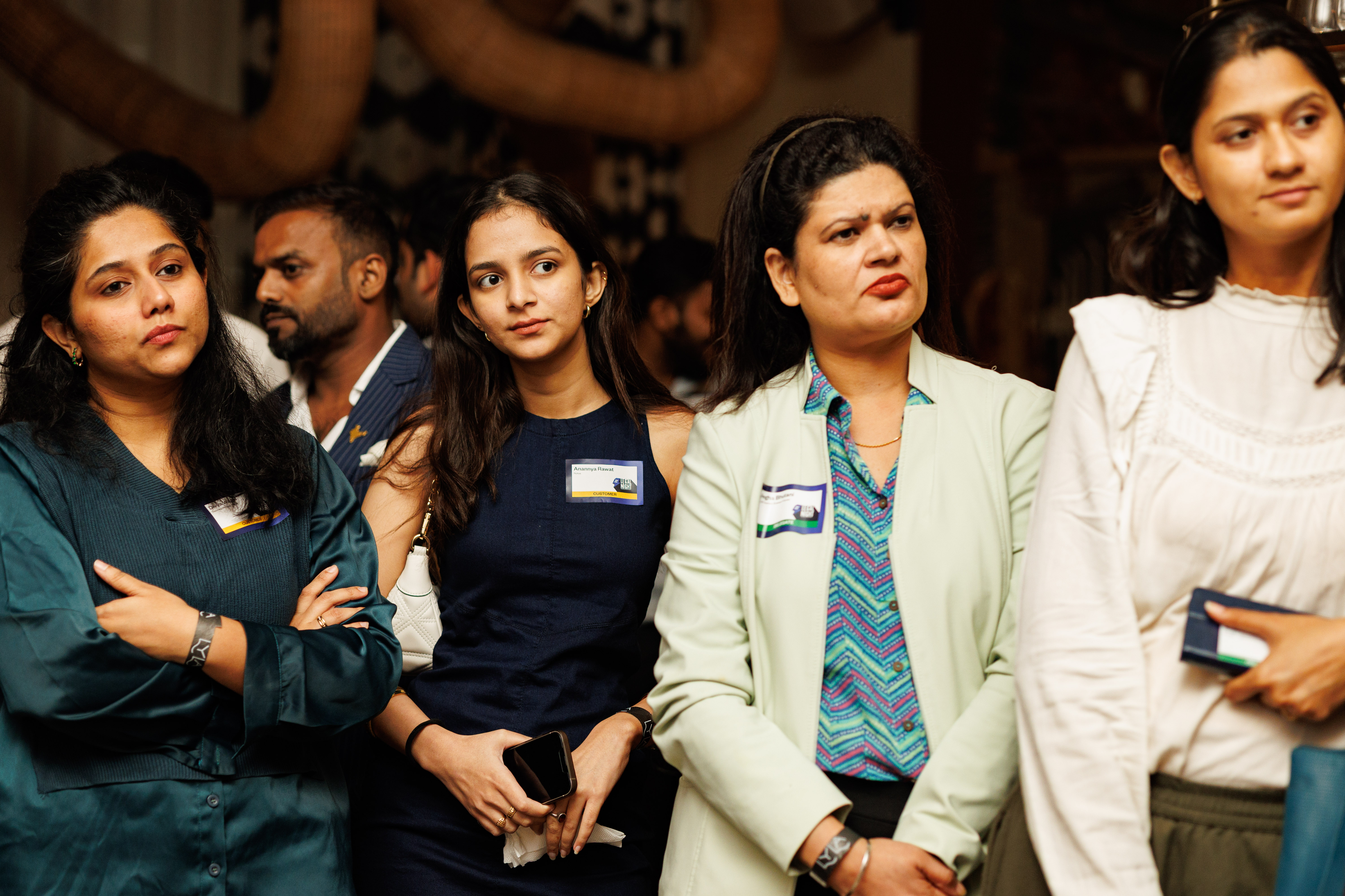 Four people standing together at an event, three women and one man in a blurred background.