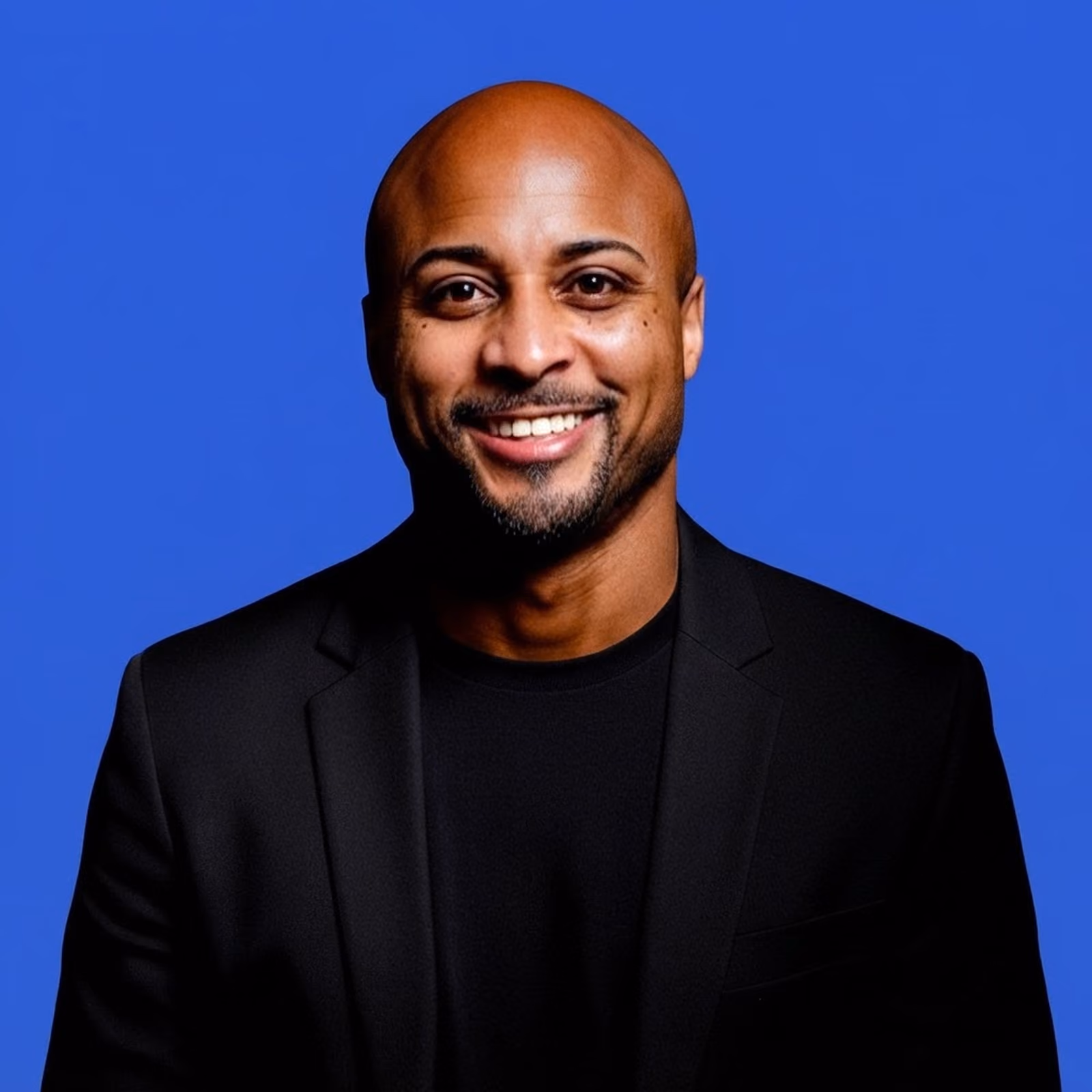 Headshot of a smiling man against a blue background