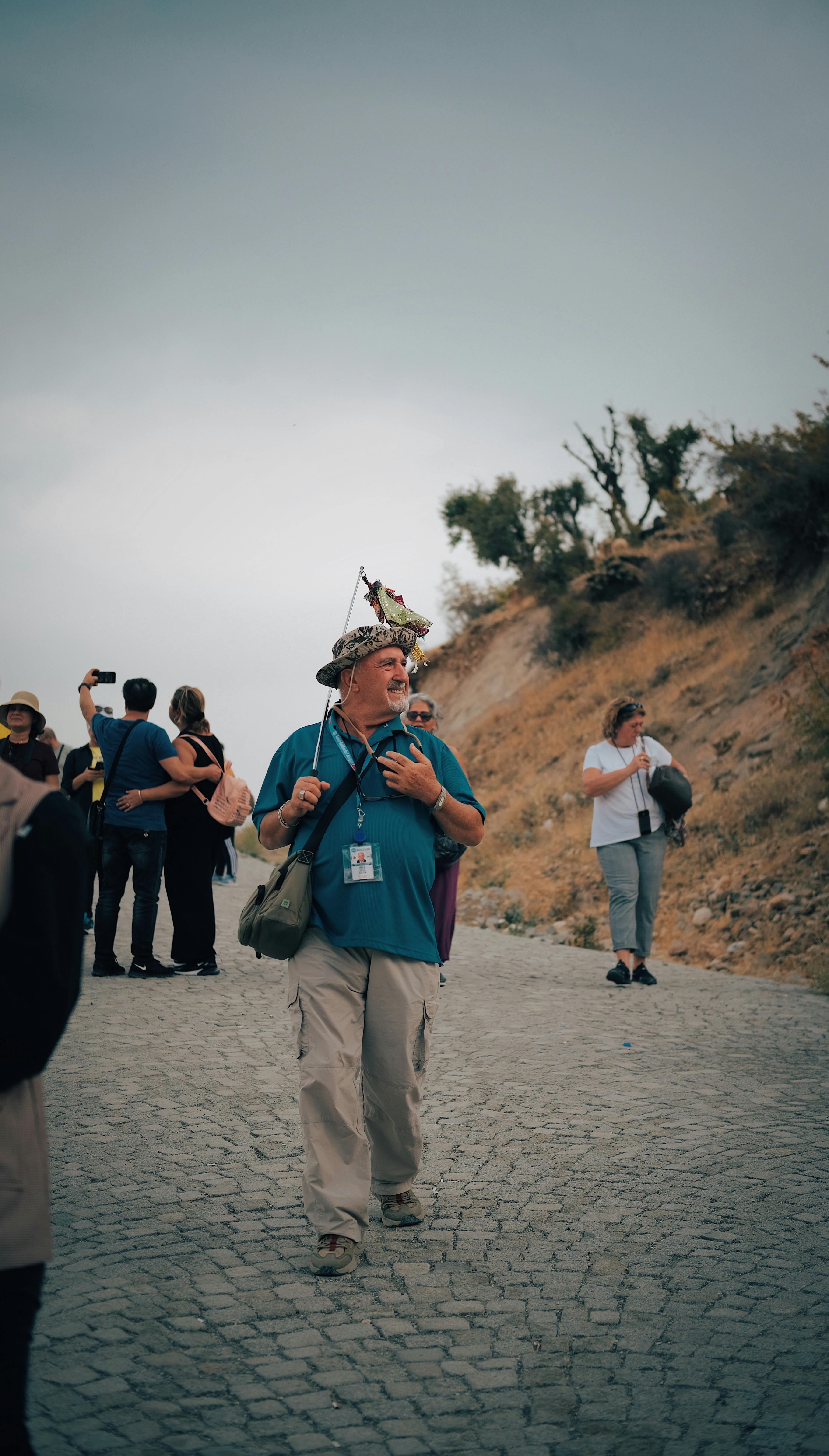 Mature man, a tour guide, walking with a group carrying a flag.