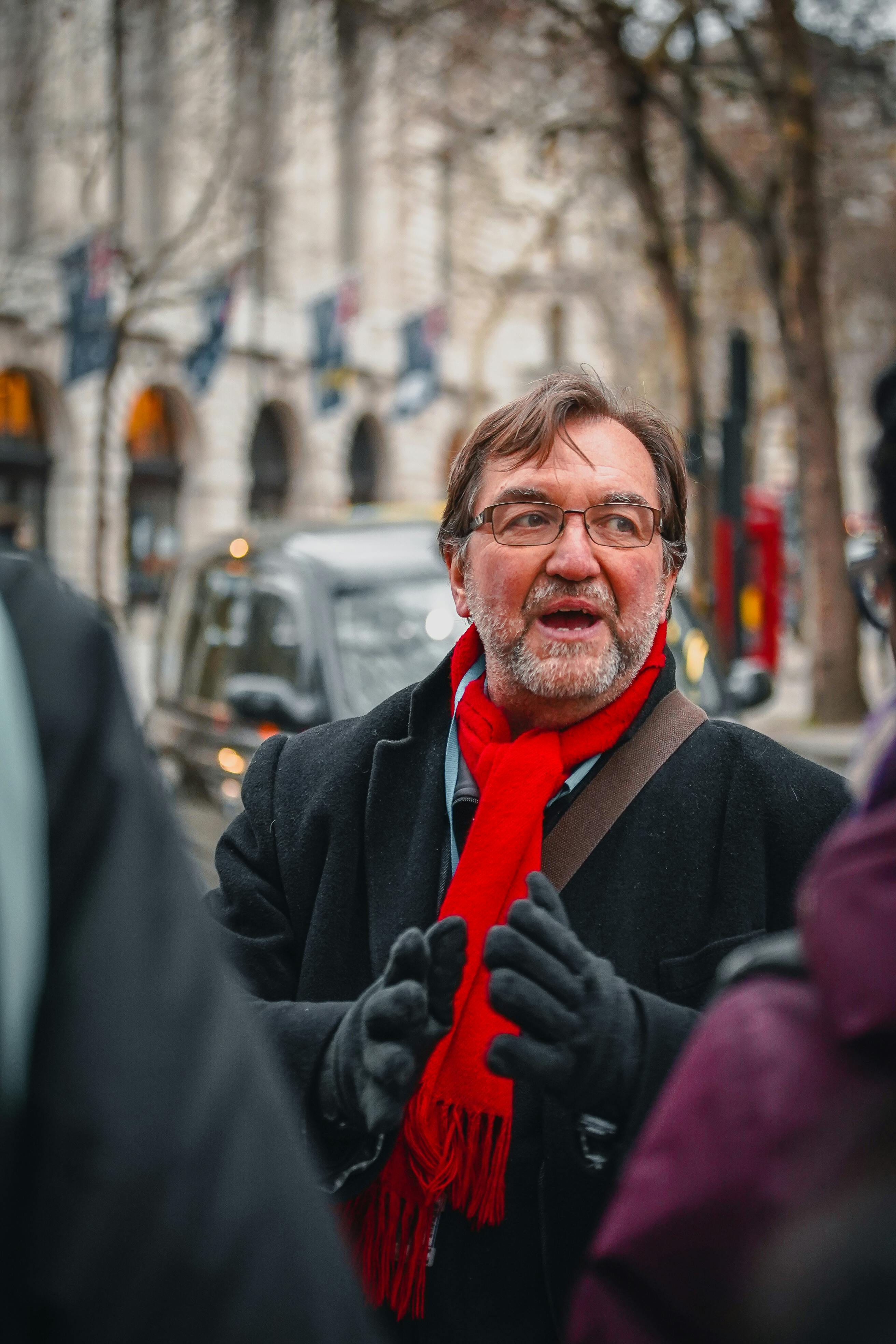 Teacher wearing a red scarf standing in the street giving a lesson outside Kings College London 