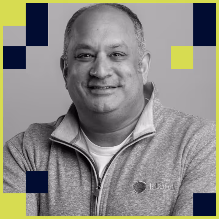Smiling middle-aged man wearing a gray zip-up jacket with the Island logo on it.